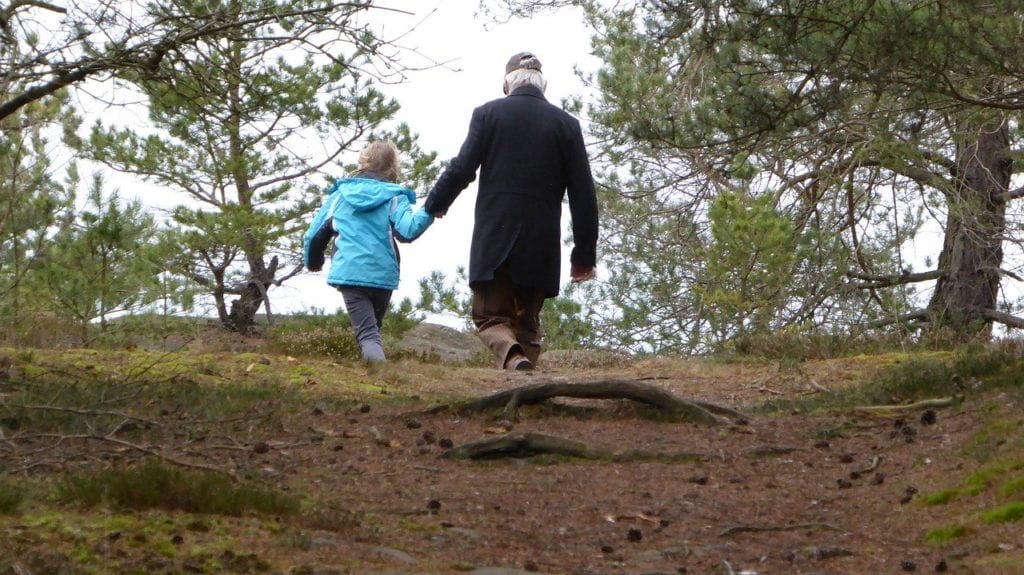 grandfather and young girl walking in the forest